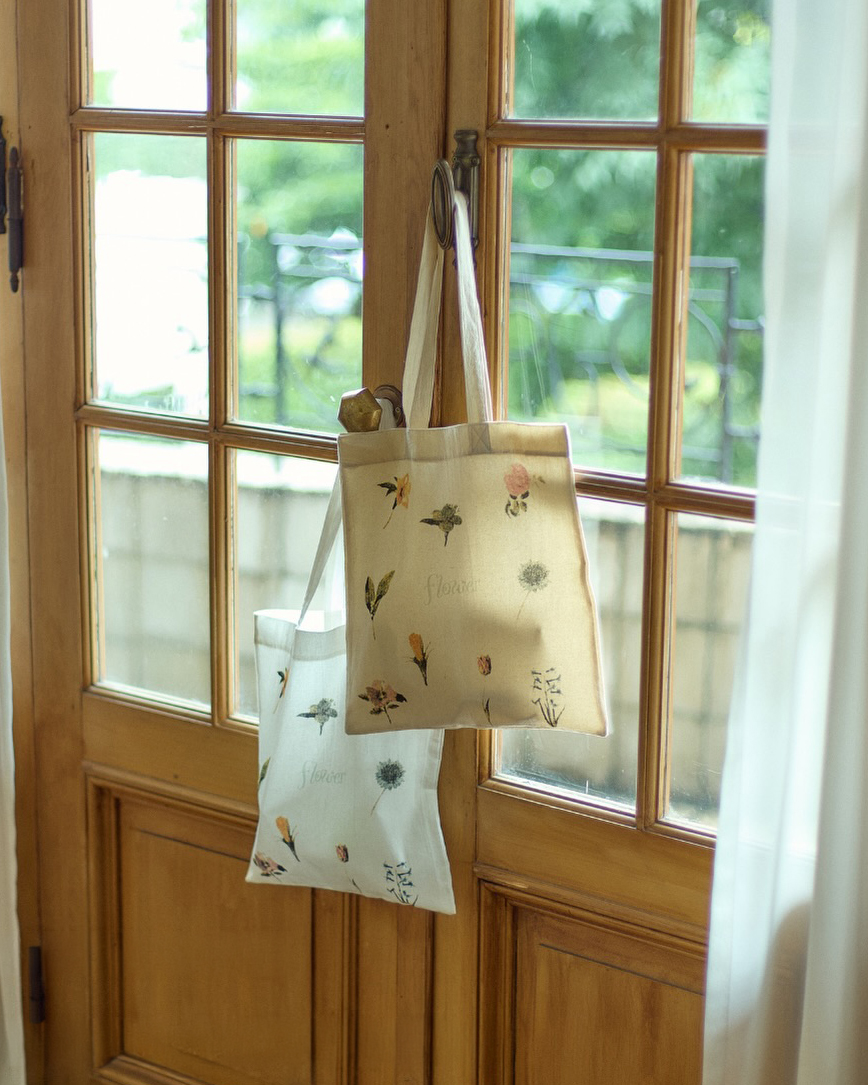 窓辺に並ぶ、花柄をあしらったflowerオリジナルトートバッグのwhiteとbeige