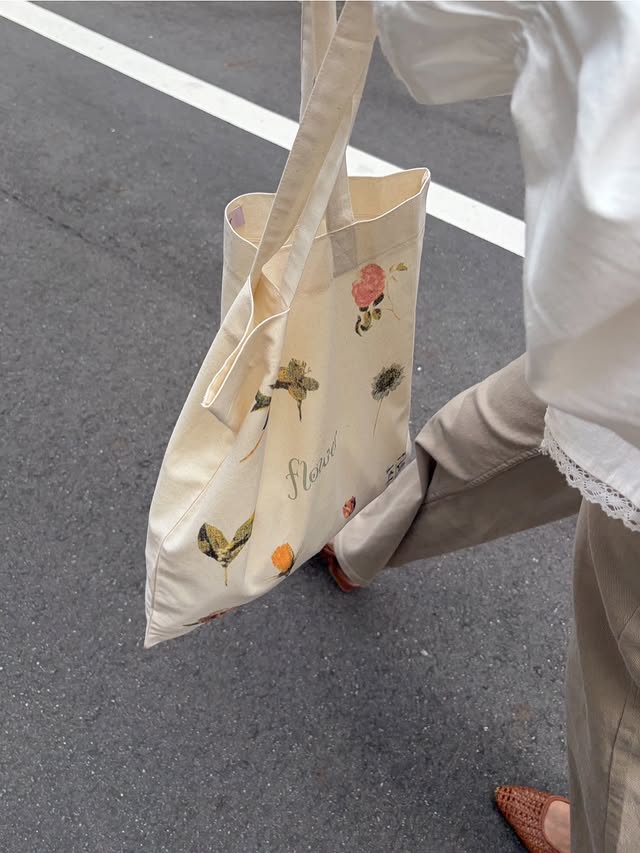 白いトップスと落ち着いた色のパンツにbeigeのトートバッグを合わせたコーディネート